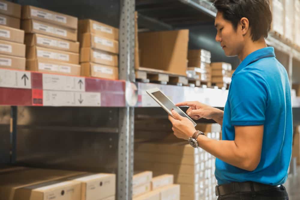 A warehouse worker using a tablet device to check stock in the warehouse